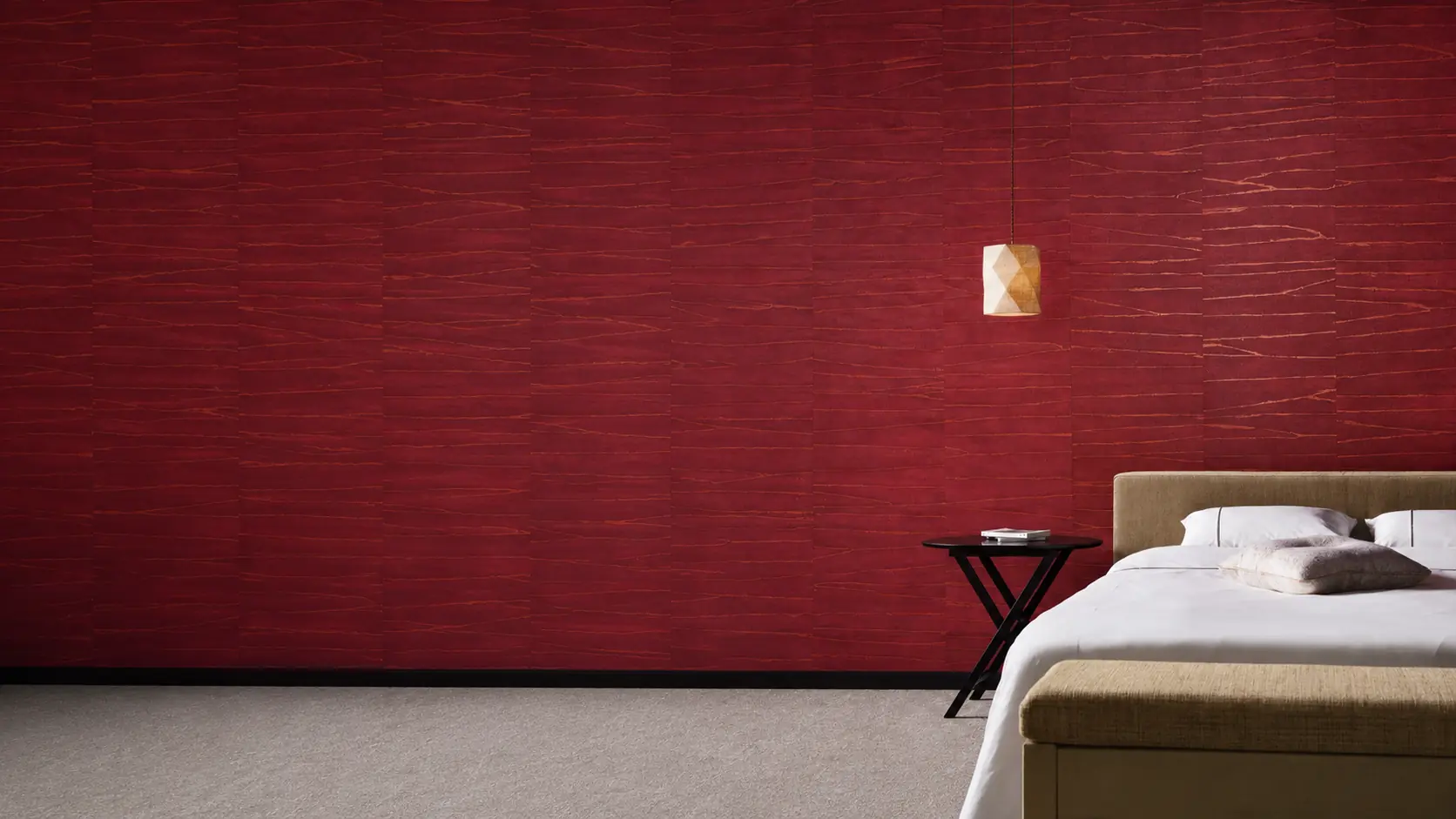 Red wallcovering beside a pendant light and an upholstered bed.