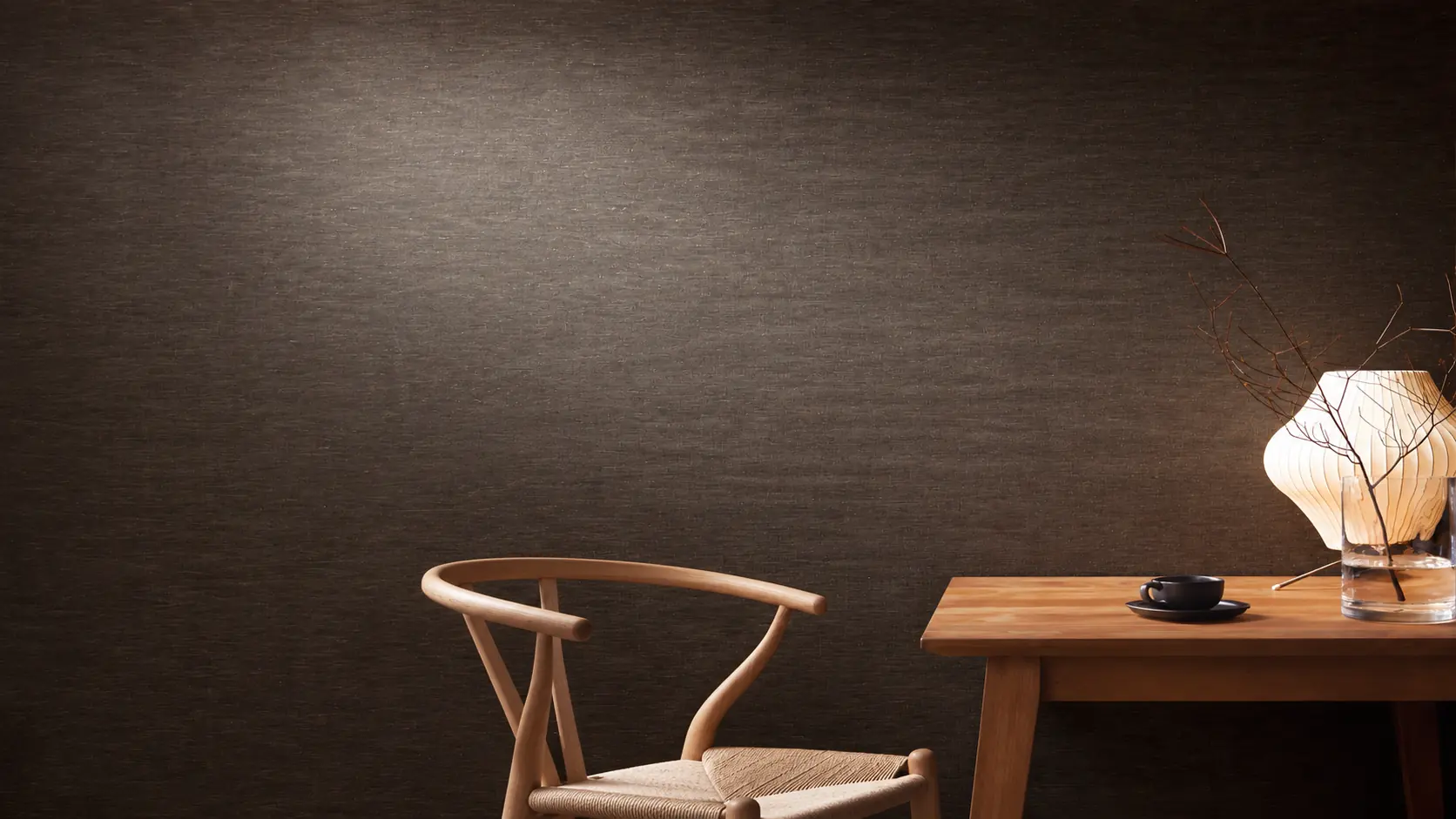 Warm woven wallcovering beside a timber table and paper lamp.