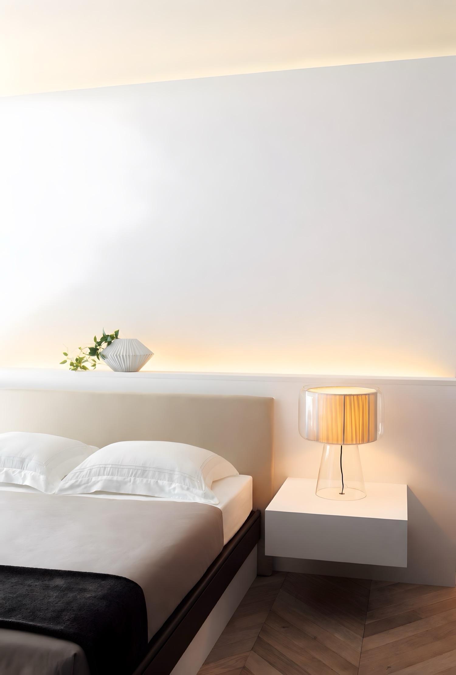 A bedroom with a lit shelf, the wall painted plain