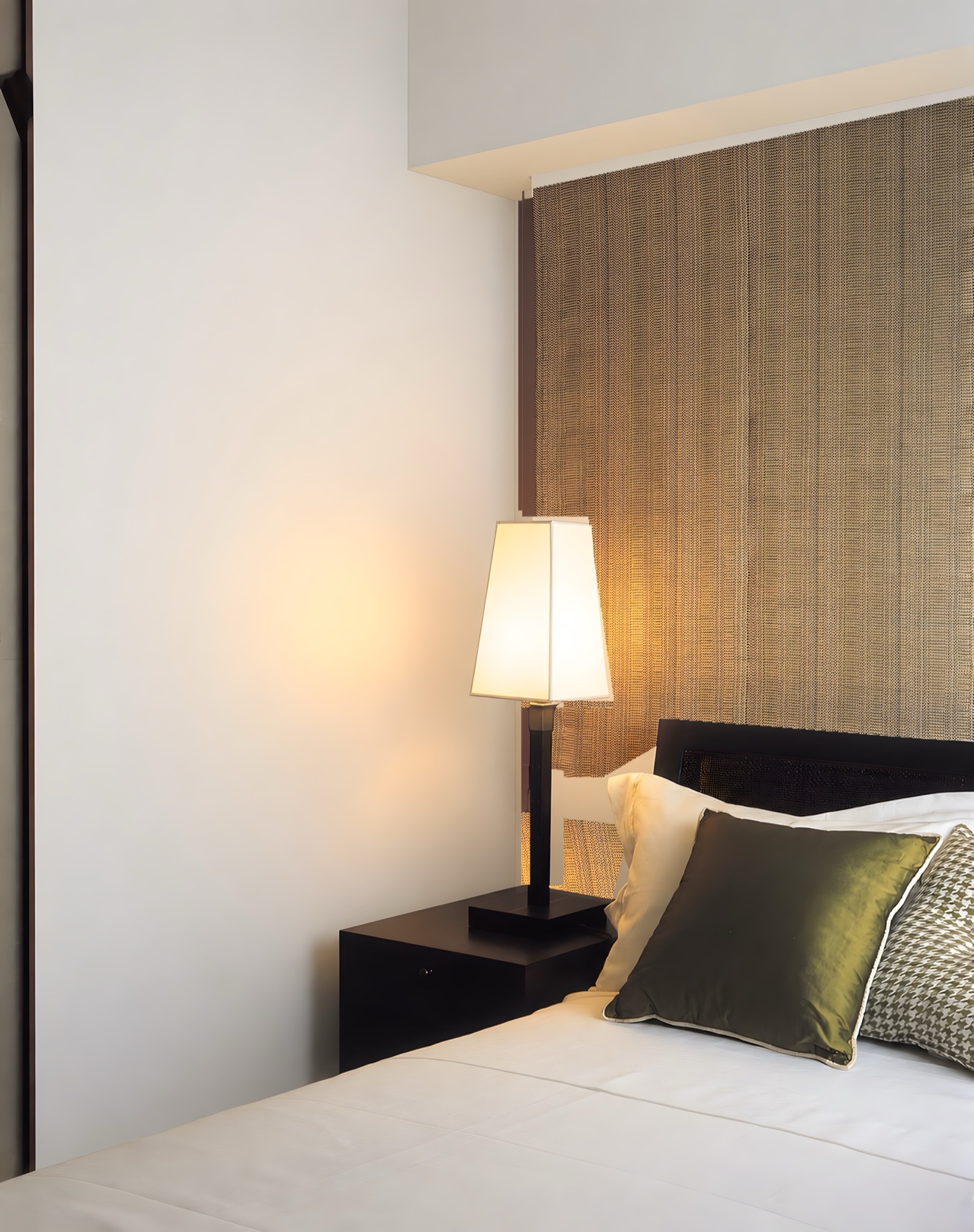 A bedside with a lamp, the wall painted plain