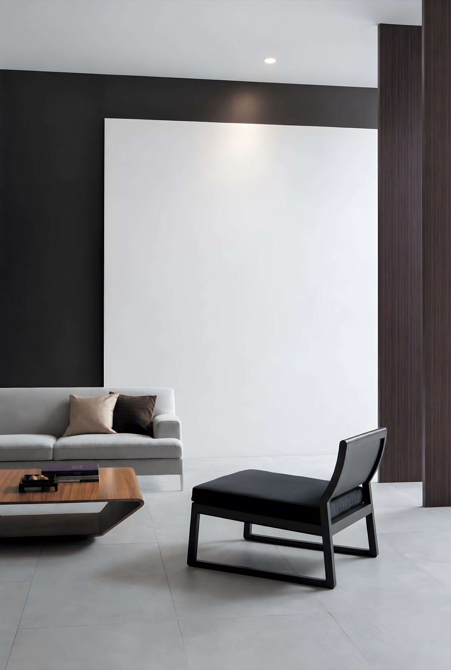 A living room with a sofa and a low chair, the wall painted plain