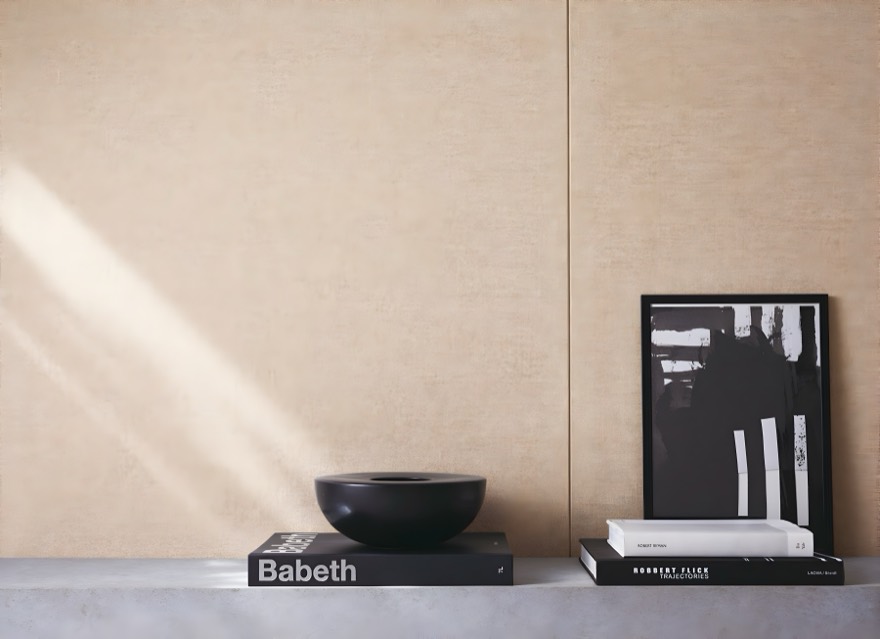 A sand-coloured linen wall above books and a black bowl